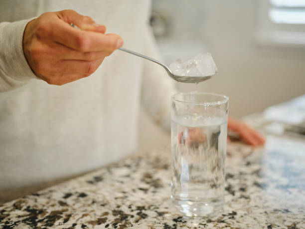 A close up of a woman removing ice from a drink.