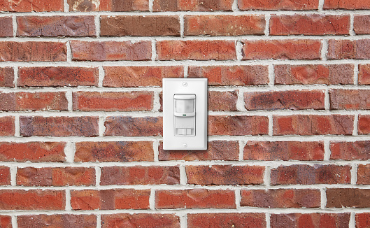 Electrical light switch sensor & dimmer on a brick wall