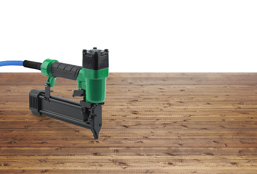 Air nailer tool on an industrial wood background