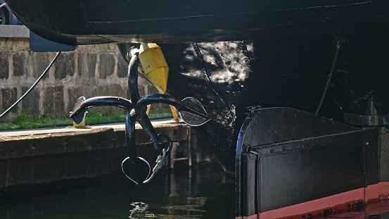 Metal Anchor Hanging by Hull of Ship Moored by Concrete Quay Wharf