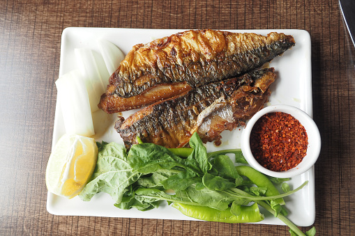 fried fish served with lettuce , lemon on a plate .