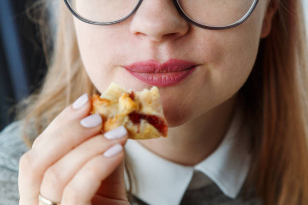 Close up of a woman mouth eating pastry dought stock photo