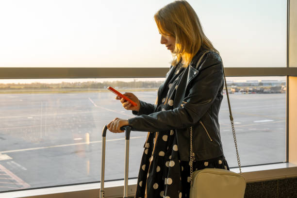 istock Woman is ready for boarding with her suitcase and checking her smartphone 1922907191
