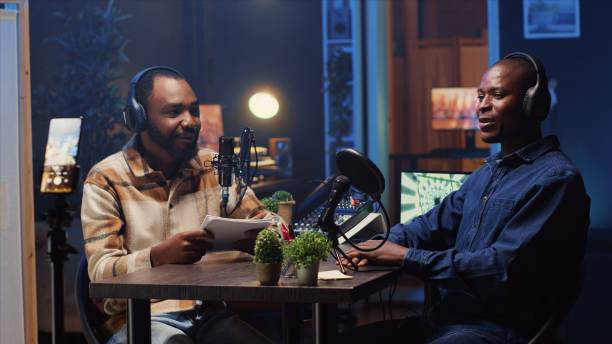 istock Man records podcast using smartphone attached to tripod and high tech microphones to interview guest 1922909300