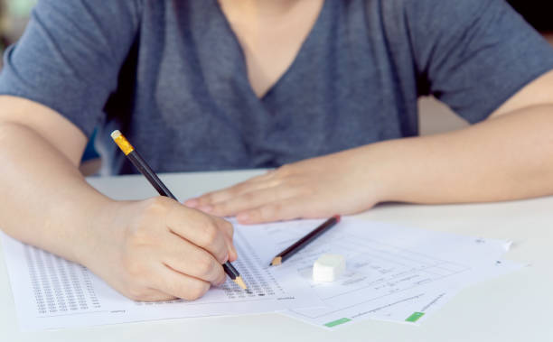istock Students hand holding pencil writing selected choice on answer sheets and Mathematics question sheets. students testing doing examination. school exam 1922923370