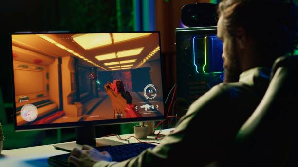 istock Man in dark living room playing engaging video games on gaming PC at computer desk 1922926476