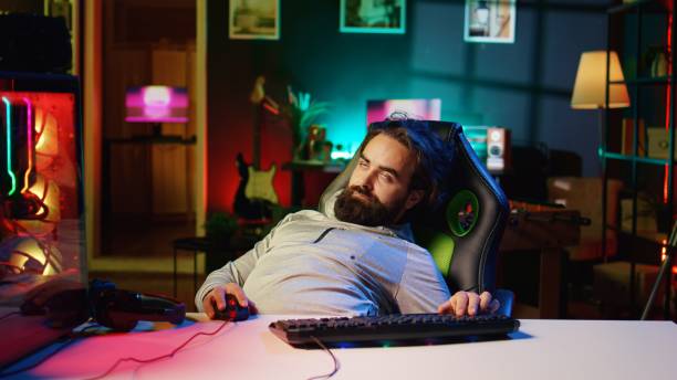 istock Man obsessed with playing videogames all day falling asleep at computer desk 1922930647