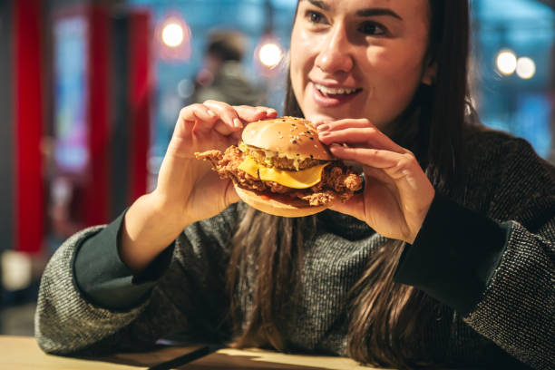 istock An appetizing chicken burger in female hands in a fast food restaurant. 1922936892