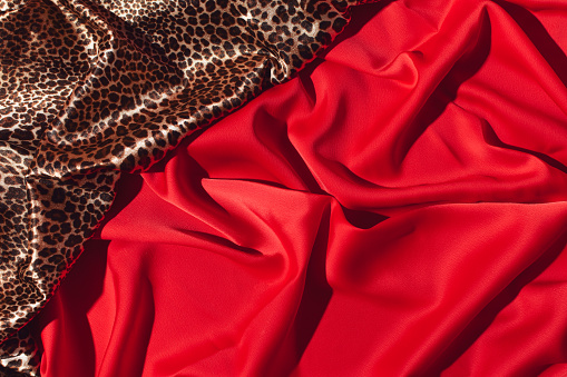 Luxurious fabrics draped, rich red and wild cat print, creative background.