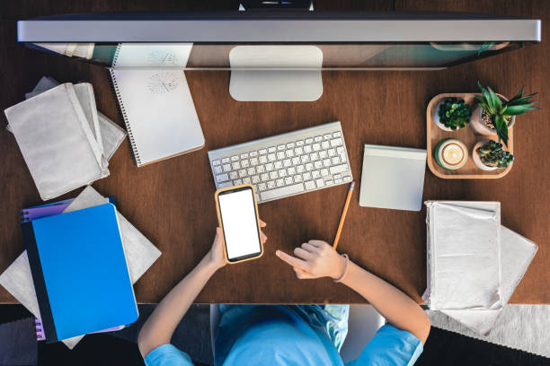 istock A schoolgirl with a smartphone sits in front of a computer, studying online. 1922952547