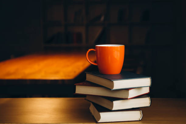 istock An orange cup on a stack of books on a dark library background. 1922964344
