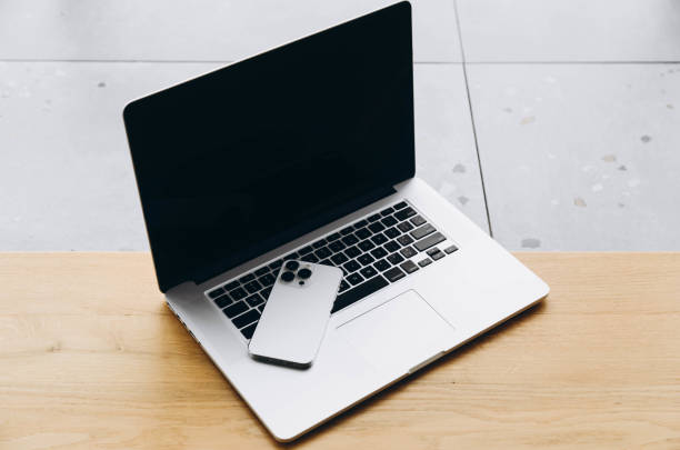 istock Open laptop and white smartphone on a wooden surface. 1922964851