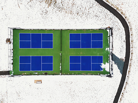 Looking down at four tennis courts in a public park in Winter.