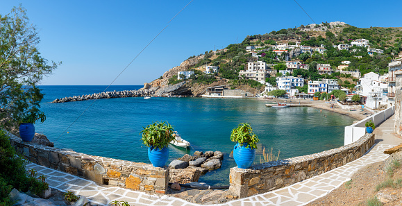 Sea view from Plaka Town on Milos Island, Greece, with whitewashed traditional houses and green vineyards on the foreground and crystal blue sky.