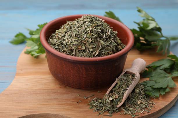 istock Dried parsley and fresh leaves on light blue table, closeup 1923063013