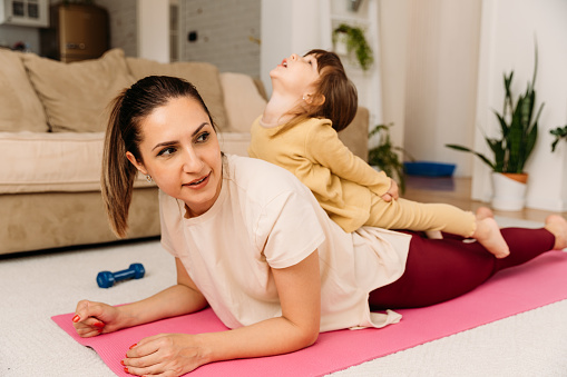 Mother and child having fun and smiling  doing exercise on a mat at home