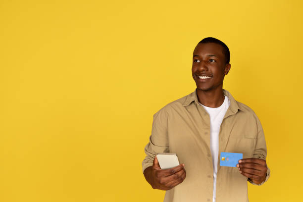 istock Cheerful pensive young black man use mobile phone and credit card 1923068870