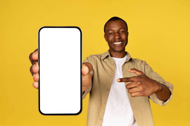 istock Cheerful young black guy in casual pointing finger at mobile smartphone with empty screen 1923068871
