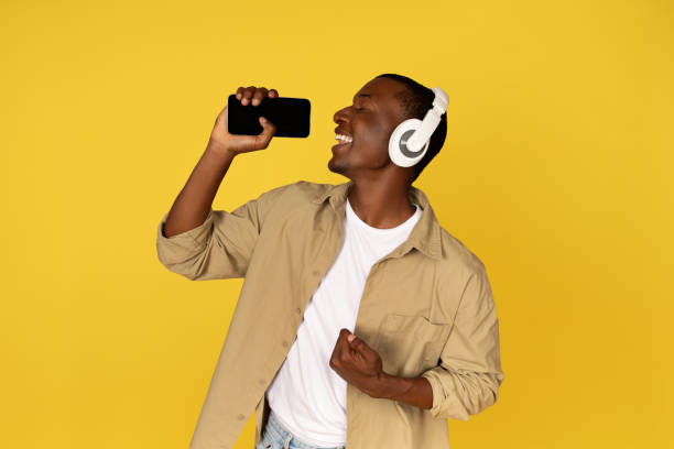 istock Cheerful young black guy in casual wireless headphones sing at mobile smartphone with empty screen 1923068882