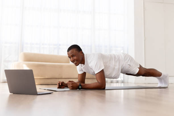 istock Happy young black man in sportswear doing workout, using laptop 1923069965