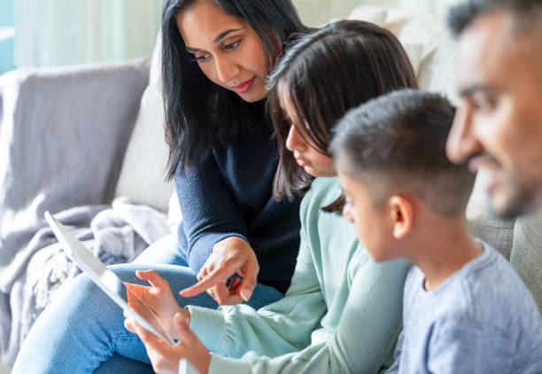 happy family with mother father and 2 children using a digital tablet on the sofa at home - father digital tablet asian ethnicity daughter imagens e fotografias de stock