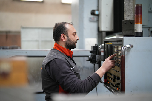 Male technician checking panel on cnc machine in industry