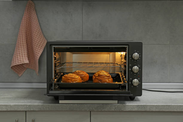 istock Open electric oven with delicious pastry on grey table in kitchen 1923121694