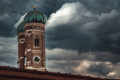 A majestic clock tower stands against a cloudy sky, with looming dark clouds in the background