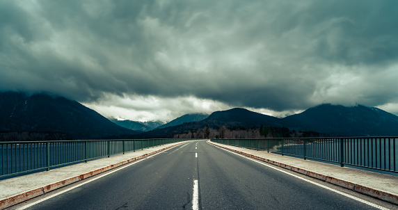 A winding highway traverses a mountain range, shrouded in a dense blanket of clouds