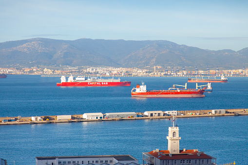 Elevated view over the Strait of Gibraltar looking over some empty oil tankers and a breakwater to the Spanish industrial and port town of Algeciras.