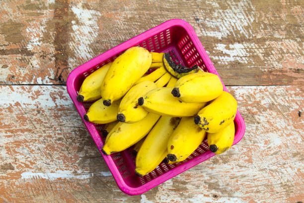 istock Bananas in a plastic basket on wooden background top view 1923195988
