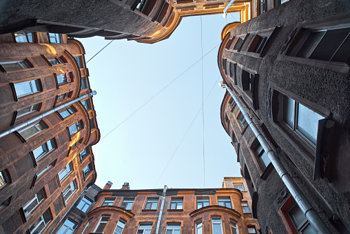View from below of old square courtyard wall in St. Petersburg, Russia. Wall, windows and part of blue sky