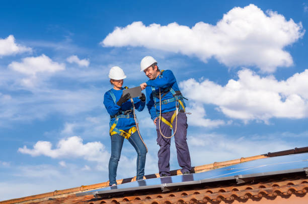 Male and female workers installing solar panels in a roof