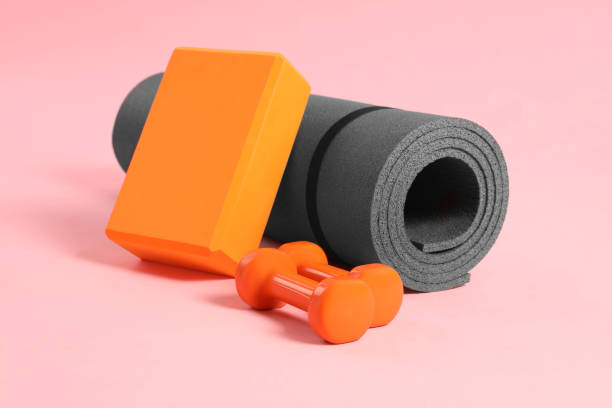 istock Grey exercise mat, yoga block and dumbbells on pink background 1923263537