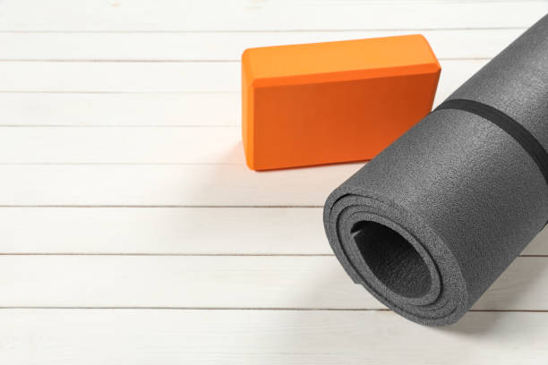 istock Exercise mat and yoga block on white wooden floor. Space for text 1923264045