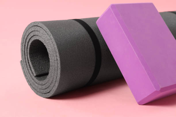 istock Grey exercise mat and yoga block on pink background, closeup 1923264573