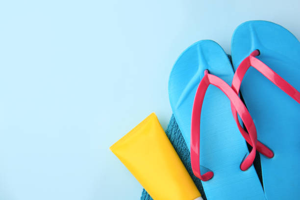 istock Towel, sunscreen and flip flops on light blue background, flat lay with space for text. Beach accessories 1923314982
