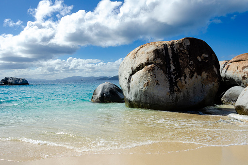 An image of the striking area known as Devils Bay & The Baths in the British Virgin Islands, renowned for its unique geological formations of giant boulders and crystal-clear tidal pools. This natural wonder, set against a backdrop of lush greenery and azure waters, creates a surreal and picturesque landscape, emblematic of the islands' breathtaking beauty.