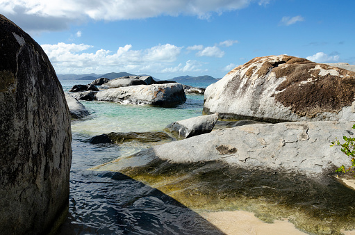 An image of the striking area known as Devils Bay & The Baths in the British Virgin Islands, renowned for its unique geological formations of giant boulders and crystal-clear tidal pools. This natural wonder, set against a backdrop of lush greenery and azure waters, creates a surreal and picturesque landscape, emblematic of the islands' breathtaking beauty.