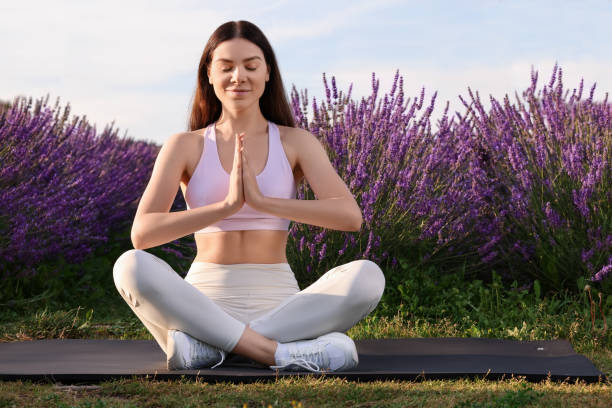 istock Woman practicing yoga near lavender outdoors. Space for text 1923333149