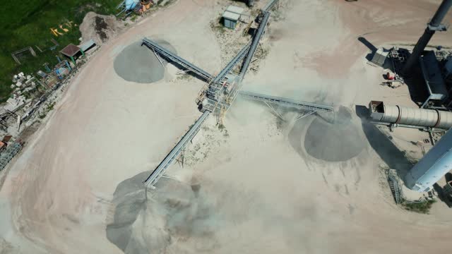 Aerial view of a cement plant at a quarry for the construction industry. Conveyor belt of heavy machinery loads gravel. Crushing plant in granite quarry top view.