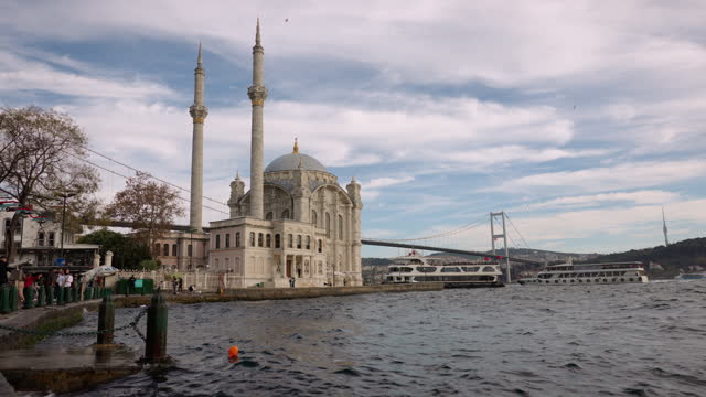Handheld Shot of Ortakoy Mosque and Bosphorus Bridge by Sea against Cloudy Sky at Istanbul,Turkey