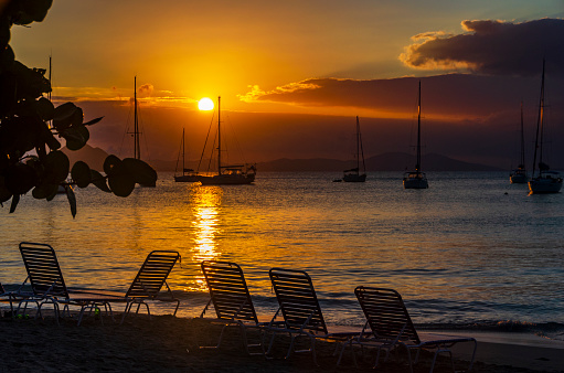 A stunning sunset in the British Virgin Islands. The sky, ablaze with vibrant shades of orange and pink, reflects on the tranquil Caribbean waters, creating a picturesque and peaceful evening scene on the sea.