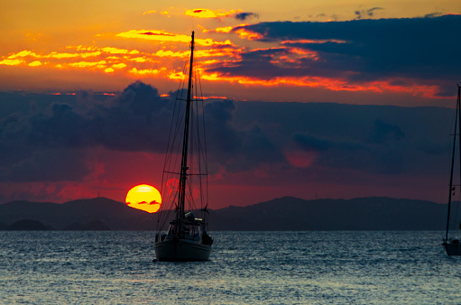 A stunning sunset in the British Virgin Islands. The sky, ablaze with vibrant shades of orange and pink, reflects on the tranquil Caribbean waters, creating a picturesque and peaceful evening scene on the sea.