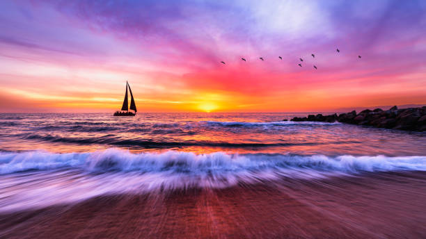 Sailboat Sunset Ocean Sea Colorful Nature Landscape Sailing Boat Inspirational Travel Journey 16:9 A Sailboat Is Sailing Along The Ocean With A Wave Breaking On Shore romantic sky stock pictures, royalty-free photos & images