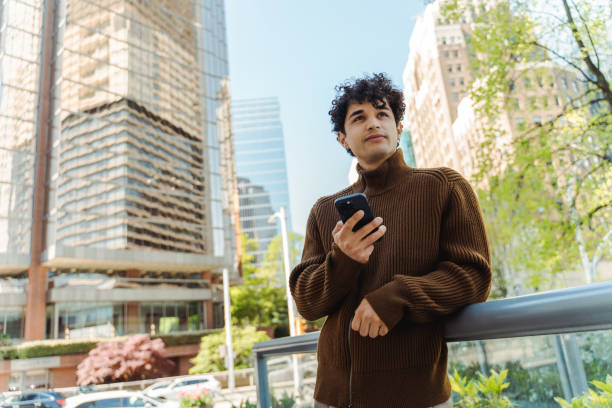 istock Handsome hispanic man holding smartphone using mobile app looking distance 1923379843