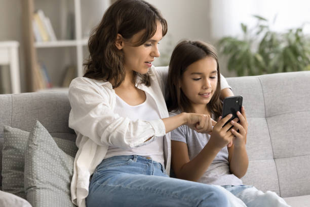 istock Engaged mom showing cute child girl how to use application 1923398331