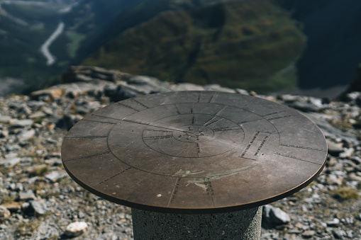 Directional dial on mountain pass above valley