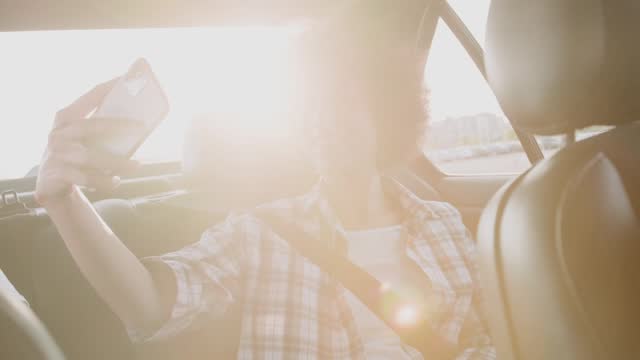 Happy woman using phone while making selfie ibn the car. Slow motion