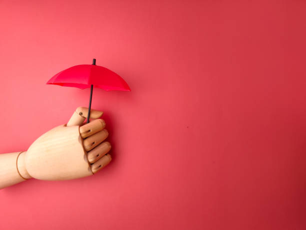 istock Wooden hand holding red umbrella on a red background with copy space. 1923435342
